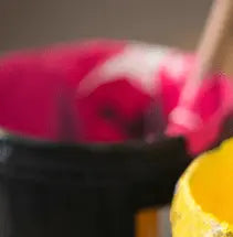 Close-up of pink water-based ink in a black bucket with yellow ink nearby, ideal for eco-friendly screen printing supplies.