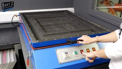 User operating a blue screen printing exposure unit with control buttons for setting exposure times.