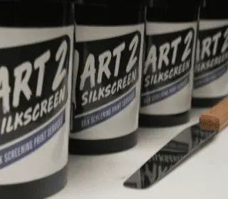Cans of ART 2 silkscreen inks with a palette knife, essential for screen printing supplies and kits.